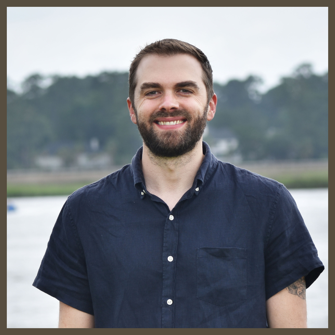 A headshot of Sean Anderson outside by the water. He is wearing a blue shirt.