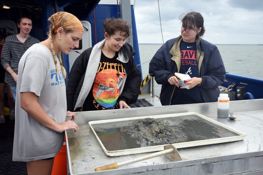 Everhart (middle) analyzing sediment from the Wassaw Sound while on a research cruise aboard the R/V Savannah during Semester at Skidaway.