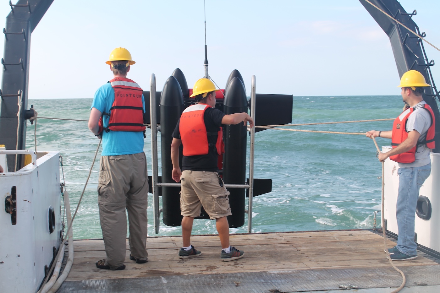 Adam Greer helping to deploy an imaging device from a research vessel.